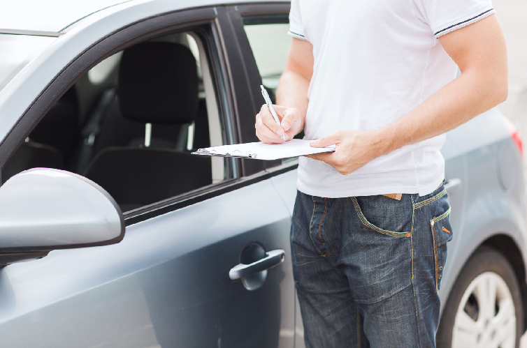 Homem ao lado de carro fazendo anotações Homem ao lado de carro fazendo anotações